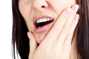 Why Does My Jaw Hurt? Woman holding her jaw in pain