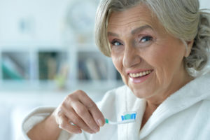 Treating Osteoporosis Can Prevent Periodontitis Old woman holding toothbrush up to mouth