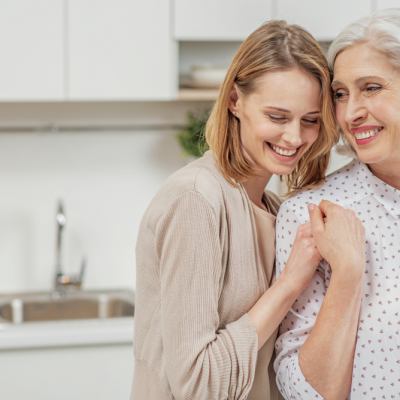 Older mother and adult daughter smiling